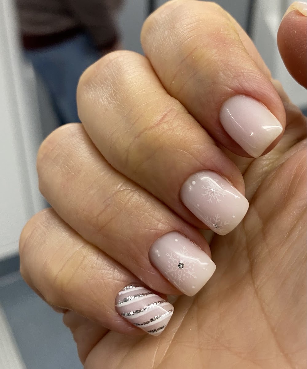 Mano con manicura francesa en tonos nude, líneas plateadas y pequeños brillantes