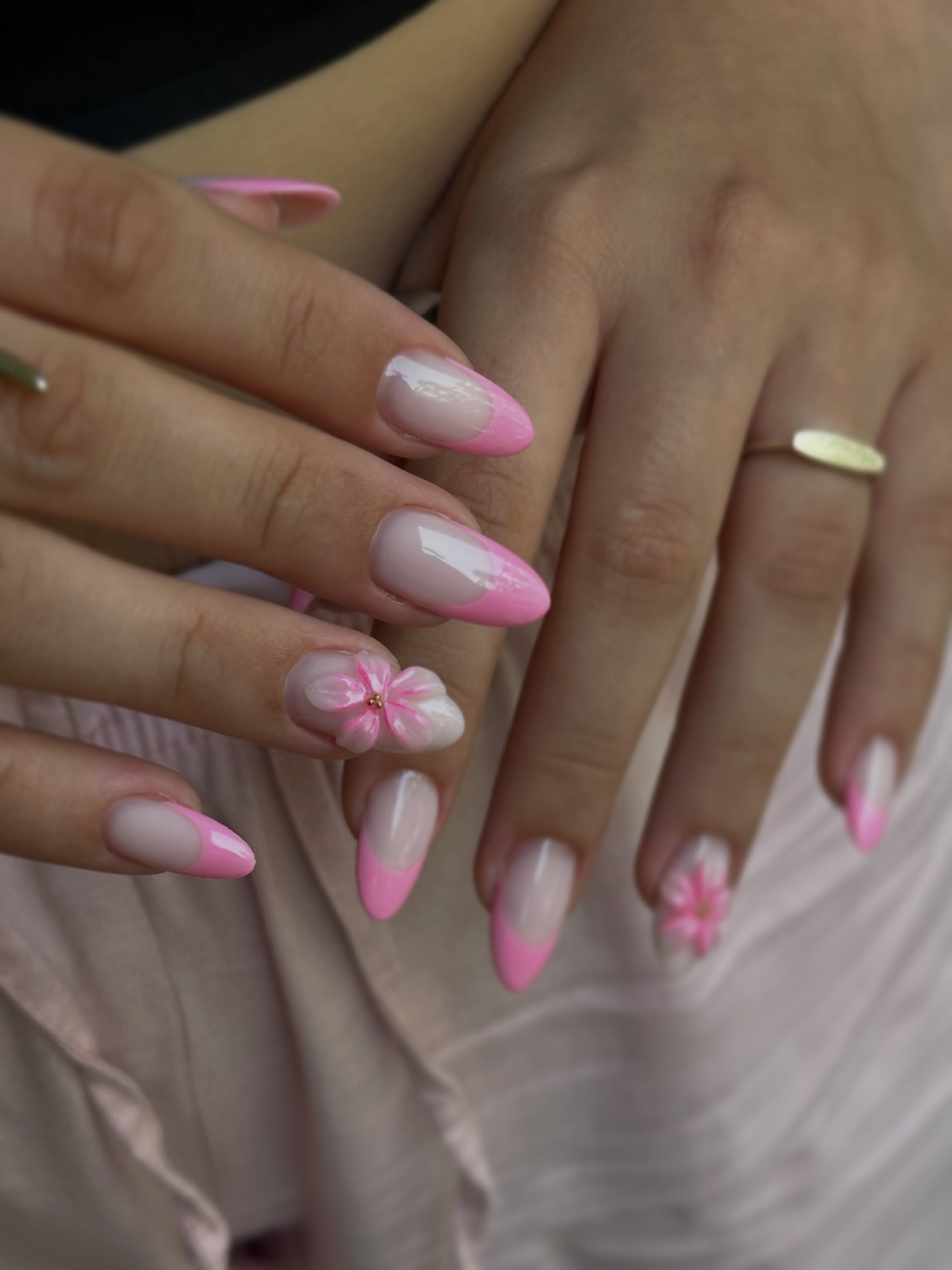 Dos manos con manicura en degradado rosa, flores pintadas en algunas uñas y forma almendrada